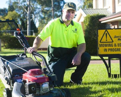 Commercial & Contract Gardening Melbourne North West: A man sitting beside a grass cutting machine, preparing for lawn maintenance.