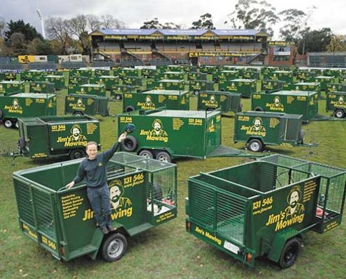 Commercial & Contract Gardening Melbourne North West: A female worker sitting on one of the many Jim's Mowing carts, surrounded by a fleet of gardening equipment.